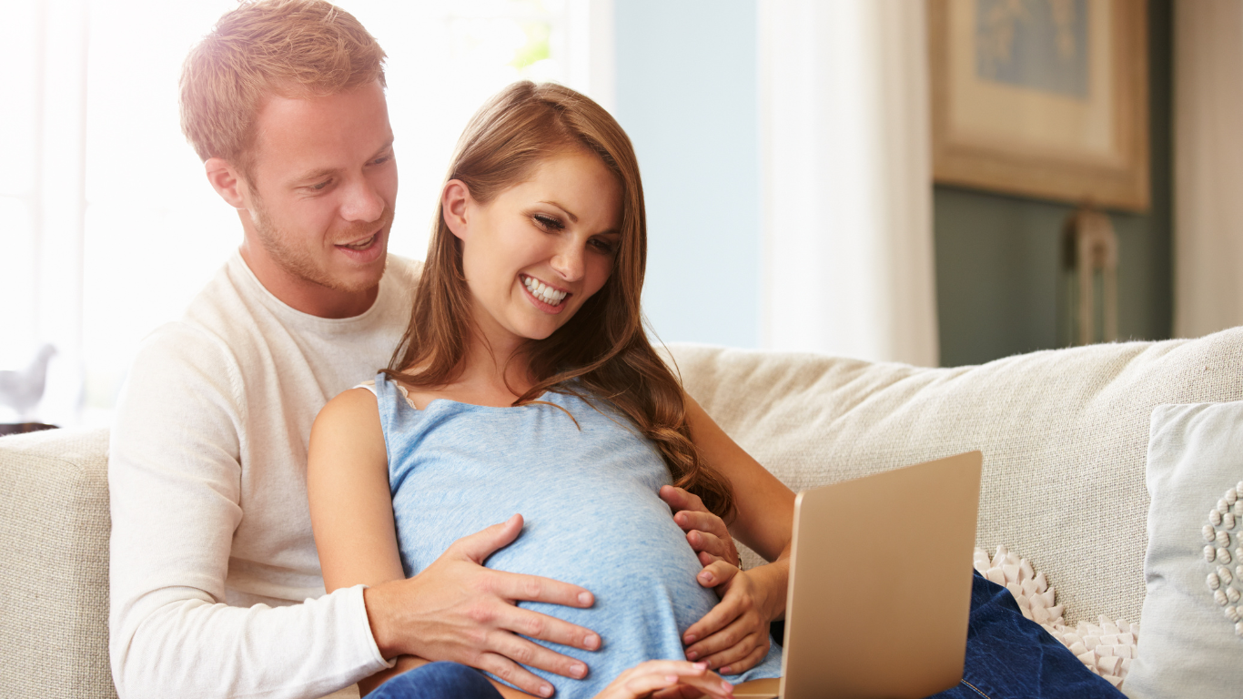 Casal na espera de um filho olhando notebook.